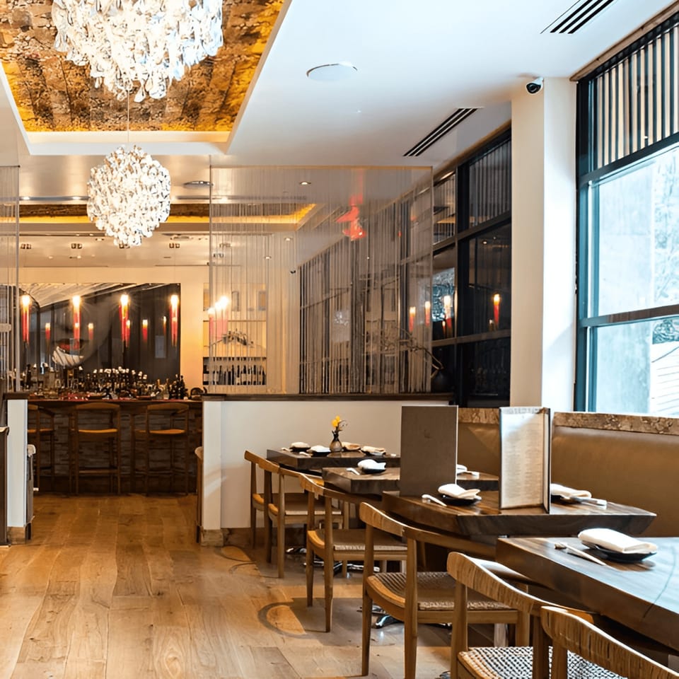 MF Sushi restaurant interior with wooden tables, chairs, a bar, and decorative chandeliers.