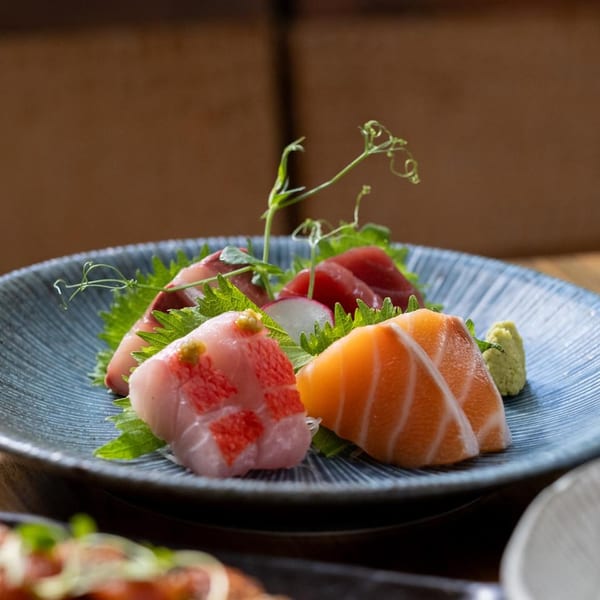 MF Sushi's sashimi platter with tuna, salmon, and white fish, garnished with greens and wasabi.